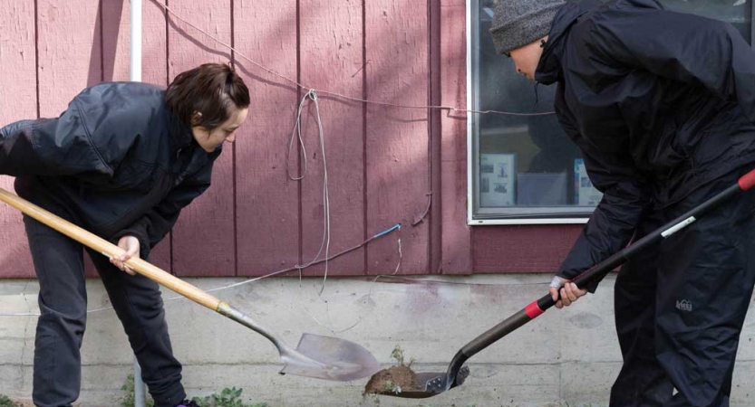 two students shovel dirt during a service project with outward bound